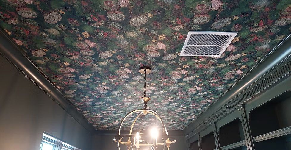 Dramatic dark floral wallpaper installed across a ceiling with a chandelier
