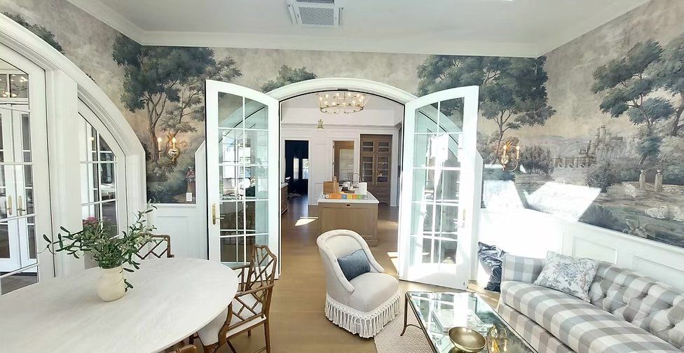 Hand-painted scenic landscape mural wrapping a formal living and dining room with arched French doors